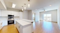 This well-designed 2-bedroom, 2-bathroom residence offers a clean, modern aesthetic throughout its efficiently utilized single-floor layout. Light wood flooring flows seamlessly across all living areas, creating a warm and cohesive feel.

The open-concept kitchen is a standout feature, showcasing white flat-panel cabinetry, quartz countertops, a central island, and a full suite of stainless steel appliances including a range, microwave, dishwasher, and refrigerator. A dedicated in-unit washer and dryer is conveniently located adjacent to the kitchen.

The living room is bright and airy, benefiting from a ceiling fan, recessed lighting, and a sliding glass door that opens to a private balcony with scenic outdoor views. Natural light pours in generously throughout the day.

Both bedrooms are well-proportioned, each featuring light wood flooring, large windows with outdoor views, and ceiling fans. The primary bedroom offers direct access to the balcony via its own sliding door. A dedicated closet provides added storage.

The two bathrooms are finished in a contemporary style, featuring white vanities with quartz countertops, tile-surround bathtubs, and light wood-style flooring. A hallway connects all rooms in a logical and functional flow throughout the residence.