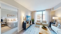 This thoughtfully designed one-bedroom, one-bathroom unit offers an efficient and modern living experience across a single floor. The open-concept layout connects the kitchen and living room, creating a cohesive and functional space. The kitchen is outfitted with stainless steel appliances, including an LG French door refrigerator, range, and over-the-range microwave, complemented by sleek white cabinetry, a herringbone-patterned tile backsplash, and clean white countertops. Light wood-tone flooring runs throughout the main living area, enhancing the bright, contemporary aesthetic.

The living room benefits from floor-to-ceiling windows that flood the space with natural light and provide views of the surrounding exterior. Neutral-toned walls and soft textiles contribute to a calm, inviting ambiance throughout. The bedroom, accessed directly from the living area, features large windows with sheer drapery, track lighting, and ample space for a full bedroom suite. A closet positioned adjacent to the bathroom provides convenient storage.

The bathroom is finished with light wood-look tile flooring, white cabinetry, and a tiled shower, maintaining the clean, modern design language found throughout the unit.