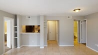 Located at 6675 Old Canton Rd in Ridgeland, Mississippi, this single-floor unit offers a practical and well-organized layout designed for comfortable everyday living. The open living and dining area is finished with light-toned ceramic tile flooring and neutral gray walls, creating a clean, cohesive aesthetic throughout. A pass-through bar connects the living space to the kitchen, enhancing the sense of openness while maintaining a defined cooking area. The galley-style kitchen features gray cabinetry, stone-look countertops, a black electric range, a built-in range hood, and a black refrigerator, with tile flooring continuing underfoot. A utility corridor off the kitchen provides access to additional storage and mechanical connections. The bedrooms are carpeted for comfort and each include a ceiling fan with light, window blinds for natural light control, and convenient closet access. The full bathroom is well-appointed with a wide vanity topped with a marble-look surface, gray cabinetry, a large mirror with overhead lighting, a full tub and shower combination, and textured walls. Built-in shelving in the hallway adds practical storage, and the layout flows efficiently from room to room. Crown molding accents the main living areas, adding a subtle architectural detail to the overall design.