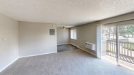Located at 1039 S Parker Rd in Denver, CO, this single-floor residence offers three bedrooms and two full bathrooms across a well-organized layout. The open kitchen and living room share a connected footprint, with the kitchen featuring warm wood-toned cabinetry, dark laminate countertops, a stainless steel sink, and white appliances including an electric range and refrigerator. Hardwood-style vinyl flooring runs through the kitchen and dining area, while the living room transitions to plush carpet. The living room is bright and open, with a sliding glass door leading to a private balcony that overlooks the surrounding community. A wall-mounted A/C unit and baseboard heating are present throughout the home. Each bedroom is carpeted and sized comfortably, with the primary bedroom featuring dual closets, including a built-in shelving unit for additional storage. Ceiling fans are installed in select bedrooms for added comfort. The two bathrooms each include a full tub/shower combination, toilet, and vanity with a warm-toned countertop. Textured ceilings are consistent throughout the unit. A hallway connects all rooms efficiently, and a breaker panel is conveniently accessible in the main living area.