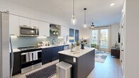 Located at 1542 Bartlett Ln in Sacramento, CA, this thoughtfully designed one-bedroom, one-bathroom residence offers a cohesive modern aesthetic across a single floor. The open-concept layout seamlessly connects the kitchen, dining area, and living room, creating a bright and functional living space. The kitchen is a standout feature, showcasing navy and white two-tone cabinetry, a geometric tile backsplash with under-cabinet lighting, stainless steel appliances, white quartz countertops, and a central island with pendant lighting overhead — ideal for both cooking and entertaining. The living room is warm and inviting, highlighted by a ceiling fan, large sliding glass doors that open to a private balcony, and abundant natural light with outdoor views. The bedroom offers a comfortable retreat with plush carpeting, a sliding barn door, large windows framing exterior views, and a dedicated closet. The bathroom features light wood-tone flooring, a sleek dark vanity with a backlit mirror, and a full tub-shower combination. Additional conveniences include an in-unit laundry area. Light hardwood-style flooring flows through the main living areas, tying together the clean, contemporary design of this well-appointed Sacramento residence.