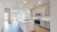 Located at 57 Caldwell Dr in Mount Holly, NC, this thoughtfully designed one-bedroom, one-bathroom residence offers a clean, contemporary aesthetic throughout its efficiently organized single-floor layout. Wood-look flooring flows seamlessly through every room, tying the space together with a warm yet modern feel.

The kitchen serves as a focal point of the home, anchored by a large center island with a white quartz countertop and an undermount sink. Gray shaker-style cabinetry lines the walls, complemented by a white subway tile backsplash and a full suite of stainless steel appliances, including a range, over-the-range microwave, and refrigerator. Recessed lighting illuminates the space, which opens directly into the living area — a bright, airy room featuring a ceiling fan and natural light from a large window with blinds.

The bedroom is a comfortable, well-proportioned retreat with its own ceiling fan, a generous window overlooking greenery, and access to a spacious walk-in closet outfitted with multi-level wire shelving for ample storage.

The bathroom is finished with the same gray cabinetry as the kitchen, a white quartz vanity top, a large mirror, and a walk-in glass-enclosed shower with tiled walls — all presented in a clean, cohesive style that carries throughout the entire residence.