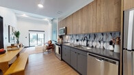 Located at 200 Euclid Ave in the heart of Cleveland, Ohio, this thoughtfully designed single-floor residence combines modern aesthetics with functional living. The open-concept layout connects the kitchen, dining, and living areas seamlessly, creating a bright and airy atmosphere enhanced by warm wood-tone flooring throughout.

The kitchen is a standout feature, outfitted with full-height wood-grain upper cabinetry, charcoal lower cabinets with black hardware, dark countertops, and a striking geometric-patterned tile backsplash. Stainless steel appliances — including a refrigerator, range, built-in microwave, and dishwasher — complete the space.

The living area is distinguished by soaring ceilings, a decorative column, and large sliding glass doors that open to a private balcony, flooding the room with natural light and providing outdoor views. The two bedrooms are tranquil and well-proportioned, each featuring wood flooring, clean white walls, and sliding glass door access to a balcony or outdoor area.

The bathroom is elegantly appointed with white subway tile walls, large hexagonal charcoal floor tiles, a wood-grain vanity with a white countertop, matte black fixtures, and a tub-shower combination — delivering a crisp, contemporary finish that ties the unit's design language together cohesively.