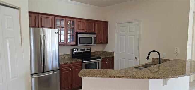 Cocina con encimeras de granito y armario para la lavadora. - 3707 Conroy Rd