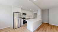 Located at 65 Paisley Blvd W in Mississauga, Ontario, this thoughtfully renovated 2-bedroom, 1-bathroom unit offers a clean, modern aesthetic throughout. Light-toned hardwood flooring runs consistently across the entire space, contributing to a bright and cohesive feel.

The open-concept kitchen and living area serves as the heart of the unit. The kitchen is fully renovated with crisp white shaker-style cabinetry extending to the ceiling, a sleek quartz waterfall island, and a full suite of stainless steel appliances including a refrigerator, range, and built-in microwave. Recessed lighting and a large window allow abundant natural light to fill the space.

The living area connects seamlessly to a private balcony via sliding glass doors, offering pleasant green views of surrounding trees. Baseboard heating is present throughout.

The primary bedroom is generously sized, featuring a sliding glass door to the balcony, filling the room with natural light. The second bedroom includes a window with a leafy outdoor view and a double-door closet for ample storage. Three closets are distributed throughout the unit.

The bathroom is finished in clean white tile, featuring a soaker tub with shower combination and modern chrome fixtures. The overall design palette — neutral walls, white trim, and light wood floors — creates a fresh, move-in-ready atmosphere.