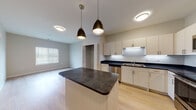 Located at 12191 Felch St in Holland, Michigan, this single-floor unit offers a thoughtfully designed open-concept layout that seamlessly connects the kitchen and living areas. The kitchen is a standout feature, equipped with stainless steel appliances including a refrigerator, range, and dishwasher, complemented by light-toned cabinetry, dark countertops, and a central island topped with a matching dark surface. Stylish pendant lights hang above the island, adding a modern touch to the space. Light hardwood flooring flows throughout the main living and kitchen areas, creating a bright and cohesive atmosphere. Natural light filters in through multiple windows fitted with horizontal blinds. The bedrooms offer plush carpeting underfoot and ample natural light, providing a comfortable and quiet retreat. Closet access is available within the bedroom spaces. The bathrooms are finished with neutral-toned tile flooring, clean white vanities with under-sink storage, framed mirrors, and brushed nickel fixtures. The overall aesthetic throughout the unit is clean and contemporary, with neutral wall tones that offer a versatile backdrop. The floor plan provides a well-organized flow between living, sleeping, and utility spaces.