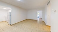 Located in Miami, FL, this single-story, one-bedroom, one-bathroom unit offers a practical and well-organized layout finished consistently with light beige ceramic tile flooring throughout. The combined living and dining area forms the heart of the unit, providing an open, airy feel with clean white walls and ceiling-mounted lighting. Natural light filters in from a balcony access point at the far end, bringing a sense of openness to the space. Adjacent to the living area, the kitchen is efficiently designed with white cabinetry, speckled quartz-style countertops, and white appliances including a refrigerator, electric range, and over-the-range microwave. A pantry provides additional storage. A dedicated den offers flexible use as a home office or secondary lounge area, and a hallway connects the main living spaces to the private quarters. The bedroom is a comfortable size, featuring a window that brings in natural light and views of surrounding greenery. Three closets throughout the unit ensure ample storage. The bathroom is outfitted with floor-to-ceiling beige tile surrounding a full soaking tub with shower, complemented by matching tile flooring and a vanity with a light stone-finish countertop.