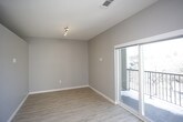 This single-floor unit presents a thoughtfully designed layout with a cohesive modern aesthetic throughout. The open-concept kitchen and living area form the heart of the space, finished with light wood-tone flooring that contrasts cleanly against neutral gray walls and crisp white baseboards. The kitchen is well-equipped with a full suite of stainless steel appliances, including a French door refrigerator, electric range, over-the-range microwave, and dishwasher. Dark espresso-toned cabinetry extends to the ceiling, complemented by open shelving, white subway tile backsplash, and light quartz countertops. A utility closet with built-in wire shelving is accessible just off the kitchen corridor, alongside an electrical panel conveniently housed in the wall. The bedroom offers a calm, functional space with the same warm flooring, gray walls, and a sliding-door closet. The bathroom features a dark wood vanity with drawers and cabinet storage beneath a white quartz countertop, an undermount sink, brushed nickel fixtures, and a large framed mirror with overhead lighting. The consistent material palette and clean finishes give the unit a polished, contemporary character throughout.