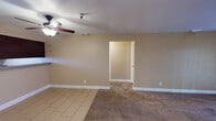 This single-floor residence offers a well-organized layout with a variety of functional spaces throughout. The living area serves as the heart of the home, featuring plush carpeting, a ceiling fan, and a tiled fireplace that anchors the room. A sliding glass door provides access to the outdoors, filling the space with natural light. Adjacent to the living area is a transition zone with tile flooring that leads into the rest of the home.

The galley-style kitchen is efficiently designed with rich dark wood cabinetry, granite-topped countertops, and light tile flooring. Black appliances, including an electric range, built-in microwave, and dishwasher, are neatly integrated throughout. A window allows natural light to brighten the workspace.

The bedrooms are carpeted and finished with warm neutral tones. Each room includes a ceiling fan with light fixture and window with blinds for natural light and ventilation. At least one bedroom features a sliding closet for added storage.

The bathrooms are consistently appointed with dark wood vanities topped with granite countertops, tile flooring, and full tub-shower combinations with white tile surrounds. Chrome fixtures and towel bars complete the clean, functional aesthetic. White trim and baseboards throughout the home provide a cohesive, polished finish.