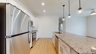 Located at 4739 Starr Ranch Rd in Indian Land, South Carolina, this single-floor residence offers a thoughtfully designed open-concept layout with modern finishes throughout. The kitchen is a standout feature, equipped with stainless steel appliances including a refrigerator, electric range, and built-in microwave. White shaker-style cabinetry, granite countertops, a subway tile backsplash, and a central island with pendant globe lighting create a stylish and functional cooking space. Light wood-style flooring runs seamlessly through the kitchen and living areas, enhancing the bright, airy atmosphere. The spacious living area benefits from a ceiling fan, large windows, and glass French doors that invite natural light and provide outdoor access. Bedrooms are finished with plush carpet flooring, ceiling fixtures, and windows with blinds that allow for natural light while maintaining privacy. The bathroom features a full tub-shower combination with white subway tile surround, granite-topped vanity, and light wood flooring, maintaining the clean aesthetic found throughout the home. The overall design is cohesive and contemporary, characterized by neutral tones, recessed lighting, and an open flow that makes the space feel welcoming and functional.