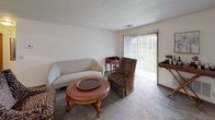 Located at 7780 S Howell Ave in Oak Creek, Wisconsin, this single-floor unit offers a practical and comfortable layout across several distinct living areas. The living room serves as the central gathering space, finished with neutral-toned carpet and featuring a sliding glass door fitted with vertical blinds that allows natural light to filter in and provides direct access to the outdoors. Built-in shelving adds a functional decorative element to one wall of the living area.

The kitchen follows a galley-style configuration, lined on both sides with warm oak cabinetry offering ample storage above and below the counter. White appliances including a range, refrigerator, microwave, and dishwasher are neatly integrated into the layout, complemented by light tile flooring and a double basin sink.

The bedroom is a calm, carpeted retreat featuring a window with garden views, providing a naturally bright atmosphere. The bathroom includes a wood-front vanity with a wide countertop, a lighted mirror, and tile flooring, creating a clean and functional space.

Throughout the unit, neutral wall tones and textured ceilings contribute to a cohesive, understated aesthetic suited to everyday living.