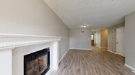 Located at 3837 SW Windsong Dr in Lee's Summit, Missouri, this two-story home presents a clean, neutral aesthetic carried consistently across both levels. The main living area is anchored by a classic fireplace framed with a white mantel and tile surround, complemented by vaulted ceilings and light wood-style luxury vinyl flooring that extends throughout the main level. Natural light filters in through blinds-fitted windows, including a front-facing window and entry door that illuminate the open living space.

The kitchen is well-appointed with crisp white shaker-style cabinetry, light countertops, and a full suite of stainless steel appliances including a range, over-the-range microwave, dishwasher, and refrigerator. A windowed back door opens to the outdoors, adding both light and convenient access. The textured ceilings are consistent throughout the home, lending a traditional character to each room.

Upstairs, the bedrooms feature plush neutral carpeting, ceiling fans, and windows that bring in natural light. The bathrooms are finished with white vanities and wood-style flooring; one includes a walk-in glass-door shower, while another offers a bathtub. A staircase connects both levels, as seen in the home's three-dimensional layout.