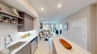 Located at Alexan Park 82nd in Doral, FL, this thoughtfully designed residence offers a seamless blend of modern aesthetics and functional living. The open-concept layout connects the kitchen, dining, and living areas, creating a bright and cohesive space ideal for both everyday living and entertaining.

The kitchen is a standout feature, appointed with sleek flat-front cabinetry in a warm taupe finish, stainless steel appliances, white quartz countertops, a tile backsplash, under-cabinet lighting, and an oversized island with bar seating. Light wood-look tile flooring flows throughout the main living areas, enhancing the airy feel.

The living room is generously proportioned, with a ceiling fan, natural light from large windows, and direct access to a private balcony with outdoor views. The dining area sits naturally between the kitchen and living space, offering a comfortable flow.

The primary bedroom features an accent wall, ceiling fan, and abundant natural light from a large window. The second bedroom is well-sized with its own window and ample room for storage. The bathroom includes a tiled walk-in shower, a vanity with quartz countertops, and clean, neutral finishes throughout.

A well-lit interior corridor leads to the unit entrance, reflecting the building's clean, contemporary design sensibility.