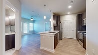 This 2-bedroom, 2-bathroom single-story residence offers a thoughtfully designed layout with modern finishes throughout. The open-concept kitchen and living area serves as the heart of the home, featuring light wood-tone flooring, recessed lighting, and a ceiling fan. The kitchen is well-equipped with dark espresso cabinetry, granite countertops, a subway tile backsplash, stainless steel appliances, and a center island with a built-in sink and pendant lighting overhead — ideal for both cooking and casual dining.

The living area extends naturally from the kitchen, bathed in natural light from multiple windows with horizontal blinds. The primary bedroom is generously sized, with wood-style flooring, a ceiling fan, and a window for natural light. Its en-suite bathroom features a walk-in shower with floor-to-ceiling tile, a granite-topped vanity, and direct access to a walk-in closet. The second bedroom features soft carpeting and a window, offering a comfortable and quiet retreat. The second bathroom includes a tiled soaking tub with a shower, a granite vanity, and tile flooring. A dedicated closet provides additional storage, completing this clean and contemporary residence.