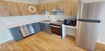 This 620 square foot apartment offers a thoughtful layout maximizing space and functionality. The modern kitchen is a standout feature, boasting a sleek design with two-tone cabinetry - light wood upper cabinets and contrasting gray lower cabinets. Stainless steel appliances, including a dishwasher and range, complement the white subway tile backsplash and quartz countertops.

The spacious bathroom is notably accessible, with multiple grab bars and a wide doorway. It features a wooden vanity with ample storage, a large mirror, and a marbled-effect floor that adds a touch of sophistication.

The 170 square foot bedroom is generously sized for the apartment, with a large window allowing natural light to flood the space. Hardwood floors run throughout the living areas, bedroom, and kitchen, creating a cohesive and warm ambiance.

The living room, while compact, feels open and airy due to its connection with the kitchen and the presence of a window or sliding door, likely leading to a small outdoor space. A wall-mounted air conditioning unit provides climate control.

Overall, this single-floor apartment combines modern amenities with a practical layout, making efficient use of its 620 square feet to create a comfortable living space.