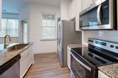 This 680 square foot apartment in Cary, NC offers a thoughtfully designed living space. The single-story unit features one bedroom and one bathroom, ideal for individuals or couples. The open-concept layout combines the kitchen and living room, creating a spacious feel. The kitchen boasts modern white cabinetry, granite countertops, and stainless steel appliances, including a side-by-side refrigerator and built-in microwave. Throughout the apartment, hardwood floors add warmth and elegance. The bedroom, measuring 140 square feet, includes a walk-in closet with wire shelving. The bathroom features a shower/tub combination with white tiling. Convenient in-unit laundry facilities are provided. Large windows with horizontal blinds allow ample natural light, while ceiling fans enhance air circulation. The neutral color palette and clean lines create a contemporary ambiance, offering a blank canvas for personalization. Located at 25510 Burbage Circle, this apartment combines modern amenities with a prime Cary location.