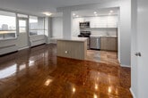 Located on the 11th floor at 155 Balliol Street in Toronto's sought-after Davisville neighbourhood, this unit offers a well-designed layout with an open, airy feel throughout. The living area is a standout feature, defined by expansive floor-to-ceiling windows that span the exterior wall, flooding the space with natural light and framing panoramic views of the Toronto skyline. Polished parquet hardwood flooring runs throughout the main living spaces, lending warmth and a classic character to the interior. A wall-mounted air conditioning unit and baseboard heating provide year-round climate control, while a balcony door provides direct outdoor access.

The kitchen has been thoughtfully renovated and features crisp white cabinetry, stone countertops with a matching backsplash, recessed lighting, and a full suite of stainless steel appliances including a refrigerator, stove, microwave, and dishwasher. A granite-topped peninsula connects the kitchen to the living area, offering additional prep and seating space.

The bedroom is generously proportioned, with its own large window framing city views and ample closet storage. The bathroom is finished in a clean, contemporary style with a white vanity, stone countertop, modern fixtures, and a decorative mosaic tile accent wall. Additional storage closets are found in the hallway, adding practical functionality to this well-appointed urban residence.