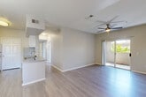 Located at 17374 N 89th Ave in Peoria, AZ, this single-story, 3-bedroom, 2-bathroom home offers a thoughtfully designed layout across a comfortable footprint. The open-concept living and kitchen area is anchored by light wood-style flooring, neutral tones, and a ceiling fan overhead. Sliding glass doors lead to a private patio, filling the space with natural light and outdoor views. The kitchen features white cabinetry, granite-style countertops, a tile backsplash, and stainless steel appliances including a range, microwave, and refrigerator, alongside a breakfast bar peninsula. The bedrooms are carpeted and include ceiling fans and windows with blinds that invite natural light. The spacious primary bedroom includes a walk-in closet with wire shelving for ample storage. Both bathrooms are finished with granite countertops, white cabinetry, and wood-style tile flooring; one includes a full tub-shower combo. A dedicated laundry room with washer and dryer hookups adds everyday convenience. A hallway connects all rooms, creating a functional and cohesive flow throughout the home.