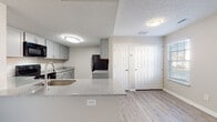 This two-floor residence at 6049 Rings Ave in Grove City, Ohio offers a clean, modern aesthetic throughout its well-appointed layout. The main level features an open-concept design where the kitchen flows seamlessly into the living and dining areas. The kitchen is outfitted with grey cabinetry, granite-style countertops, a peninsula with an undermount sink, and black appliances including a range, microwave, and refrigerator. Wood-look vinyl plank flooring extends throughout the main level, complementing the neutral wall tones and textured ceilings. Multiple windows along the front of the living area fill the space with natural light, creating a bright and welcoming atmosphere. A staircase connects the main level to the upper floor, where the bedrooms are located. Each bedroom features plush carpeting, neutral walls, and windows that allow in natural light. The bathrooms are finished with grey vanities topped with granite-style counters, wood-look vinyl plank flooring, and a full soaking tub with shower in the full bath. Chrome hardware and fixtures add a polished touch throughout. The overall design is cohesive and contemporary, offering a comfortable and functional living environment.