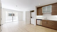 This well-designed one-bedroom, one-bathroom unit offers a clean, modern aesthetic throughout its efficiently laid-out single floor. Light wood-tone flooring flows through the open-concept living and kitchen area, creating a bright and cohesive atmosphere enhanced by recessed lighting and sliding glass doors that connect the living space to an outdoor area.

The kitchen is a standout feature, showcasing rich wood-grain cabinetry with frosted glass upper panels, a crisp white countertop, and a full suite of stainless steel appliances including a gas range, dishwasher, and refrigerator. Conveniently tucked behind a louvered door adjacent to the kitchen is an in-unit stacked washer and dryer, adding practical functionality to the space.

The bedroom is a comfortable, well-proportioned retreat with light wood flooring and a sliding glass door that provides access to an exterior area and fills the room with natural light. A dedicated walk-in closet is outfitted with adjustable wire shelving and hanging rods, offering well-organized storage.

The bathroom features a combination tub and shower enclosed by a sliding glass door, with clean white tile surround, a wood-grain vanity with an undermount sink, and neutral tile flooring, maintaining the modern and cohesive design found throughout the unit.