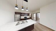 This well-designed 2-bedroom, 2-bathroom single-floor unit offers a functional and modern living experience. The open-concept kitchen and living area serves as the heart of the unit, featuring rich dark-brown cabinetry, stainless steel appliances including a refrigerator, electric range, and microwave, and a striking marble-look countertop island with a double stainless steel sink. Stylish pendant lights with gold-toned accents hang above the island, adding a contemporary touch to the space. Wood-style plank flooring flows seamlessly throughout the entire unit, providing warmth and visual continuity.

The two bedrooms are comfortably sized, with the primary bedroom offering a dedicated closet with built-in shelving. Each room features neutral white walls, clean lines, and windows that bring in natural light. One bedroom also includes a sliding double-door closet for convenient storage.

The bathrooms echo the kitchen's design aesthetic, with dark cabinetry vanities, light countertops, and clean white fixtures. A stacked washer and dryer unit is conveniently located within the unit. The overall ambiance is clean, modern, and move-in ready, with a cohesive neutral palette and practical layout throughout.