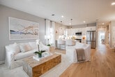 Located at 910 Sipp Ave in East Patchogue, NY, this well-appointed single-story home offers three bedrooms and two bathrooms within a thoughtfully designed open-concept floor plan. Light oak hardwood flooring flows seamlessly throughout the main living areas, creating a warm and cohesive aesthetic. The combined kitchen and living room serves as the heart of the home, featuring white shaker cabinetry with matte black hardware, quartz countertops, a subway tile backsplash, stainless steel appliances, and a central island with bar seating — all bathed in natural light from multiple windows. The living area is generous and inviting, anchored by a built-in wood shelving unit that adds both function and character. The primary bedroom is a comfortable retreat with hardwood floors, recessed lighting, and a sliding glass door that opens to a private outdoor patio with yard views. Both bathrooms are finished with large-format marble-look porcelain tile flooring, white vanities with matte black fixtures, and glass-enclosed or tub-shower combinations. A dedicated closet provides additional storage. The home's clean, neutral palette and coastal-inspired design elements give it a bright, airy ambiance throughout.