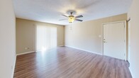Located at 500 Rasco Rd W in Southaven, MS, this single-floor residence offers a practical and comfortable layout across three distinct living areas. The living room serves as the heart of the home, featuring warm hardwood-style flooring, a ceiling fan with integrated light fixture, a textured ceiling, and a full-length sliding glass door dressed with vertical blinds that allows natural light to fill the space. An open sightline connects the living room directly to the kitchen, enhancing the sense of openness throughout. The kitchen is well-appointed with white cabinetry extending to the ceiling for ample storage, a double-basin stainless steel sink, speckled laminate countertops, and white appliances including a range, dishwasher, and refrigerator. Hardwood-style flooring continues through the kitchen, which also benefits from a window and exterior door that bring in additional natural light. The bedroom offers a quieter retreat with soft carpeting underfoot and neutral-toned walls that create a calm, restful atmosphere. The warm beige color palette used consistently throughout the unit ties each space together, resulting in a cohesive and inviting interior.