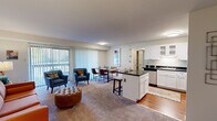This thoughtfully designed 2-bedroom, 2-bathroom residence offers a functional and comfortable single-floor layout. The open-concept living, dining, and kitchen area serves as the heart of the home, where the kitchen stands out with white shaker-style cabinetry, dark countertops, stainless steel appliances including a refrigerator, electric range, microwave, and dishwasher, and warm hardwood flooring. A peninsula with bar seating provides a seamless transition into the dining and living areas, which feature plush carpeting and large sliding glass doors that invite abundant natural light and outdoor views. The primary bedroom is a generously sized retreat with a large window, carpeted flooring, and a dedicated closet. The second bedroom also offers carpeted flooring and a full-width closet, making it versatile for various uses. Both bathrooms are finished in clean white tile, each featuring a vanity and a tub-shower combination. A hallway connects the private sleeping quarters to the main living areas, and two closets provide additional storage throughout the residence. The overall ambiance is bright, clean, and welcoming, with a practical layout that maximizes every square foot.