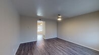 This two-floor space combines practical design with updated finishes throughout. The main living areas feature dark hardwood-style flooring that extends seamlessly between rooms, complemented by neutral-toned walls and textured ceilings. Ceiling fans are present in multiple rooms, providing both light and air circulation. A staircase connects the two levels, visible from the main living area, which also benefits from natural light through blinds-fitted windows.

The kitchen is notably well-appointed, featuring gray cabinetry with modern hardware, light speckled countertops, a classic white subway tile backsplash, and black appliances including an electric range, microwave, and dishwasher. The wood-style flooring continues into this space, maintaining visual continuity.

The bedrooms are carpeted and generously sized, each offering windows that allow natural light to filter in. Ceiling-mounted light fixtures add warmth to these rooms. The bathrooms include wood-look vinyl flooring, a tub-shower combination in one, and a more compact layout in another, both finished in neutral tones. A hallway connects the upper-level sleeping areas, providing easy access to the bathrooms and additional storage.