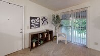 This single-floor residence offers a thoughtfully laid-out interior designed for comfortable everyday living. The galley-style kitchen is equipped with warm honey-toned wood cabinetry, granite-look countertops, wood-look flooring, and full white appliances including a refrigerator, electric range, and dishwasher — providing ample storage and workspace in an efficient footprint.

The open living and dining area creates a natural flow for entertaining. The dining space features a ceiling fan and a distinctive arched mirror trio mounted on a half-wall partition, adding architectural character. The living room is carpeted and benefits from a sliding glass door that fills the space with natural light and provides views of lush greenery outside.

Multiple bedrooms are carpeted and feature textured ceilings, neutral walls, and natural light from windows. Each room offers generous space for bedroom furnishings and personal storage.

The bathrooms are finished with matching warm wood vanity cabinetry, granite-look countertops, and well-lit vanity mirrors. One bathroom includes a shower/tub combination, while another features a dedicated vanity corridor for added privacy and functionality. Wood-look flooring completes the bathrooms' cohesive aesthetic, tying together the warm, earthy tones found throughout the residence.