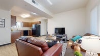 This single-floor residence offers a thoughtfully designed layout that balances comfort and functionality throughout. The open-concept living area is bright and welcoming, featuring light wood-style flooring, neutral walls, and soaring vaulted ceilings that lend a sense of spaciousness. Large windows allow natural light to fill the room, creating an airy atmosphere ideal for both relaxing and entertaining.

The kitchen is well-equipped with rich wood cabinetry, ample counter space, and a full suite of black appliances including a refrigerator, range, and dishwasher. A window above the sink brings in additional natural light, while the light hardwood flooring ties the space seamlessly to the living area.

The bedrooms are carpeted for comfort, each featuring windows with outdoor views of surrounding trees and generous closet space, including sliding-door closets with built-in hanging rods. The neutral color palette throughout creates a calm and versatile environment.

Two full bathrooms are finished with clean, wood-look vinyl flooring, full tub and shower combos, and windows for natural ventilation. A dedicated laundry area houses a stacked washer and dryer unit alongside a folding shelf, adding everyday convenience to this well-rounded residence.