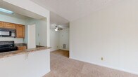 Located at 3430 Norfeld Ct in Virginia Beach, Virginia, this single-floor residence offers a clean, functional layout designed for comfortable everyday living. The entryway opens into a bright living area finished with neutral-toned wall-to-wall carpet and a textured ceiling. A ceiling fan serves the open living and dining space, which connects seamlessly to the kitchen via a pass-through countertop with granite-style laminate surfaces, providing a convenient bar-style interface between the rooms. The galley-style kitchen is efficiently arranged with warm wood cabinetry, dual-basin sink, granite-look countertops, and a full suite of black appliances including a refrigerator, electric range, microwave, and dishwasher, all set on light tile flooring. The bedrooms are spacious and carpeted, each featuring windows that allow natural light to fill the rooms. The primary bedroom offers generous storage with both a walk-in closet and an additional shelved closet, along with a private en-suite bath. The bathroom features a wood-toned vanity with a white countertop, an oversized mirror, and clean white finishes throughout. Throughout the residence, neutral white walls, soft carpeting, and consistent finishes create a cohesive and move-in ready atmosphere.