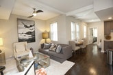 Located at 130 Brooke Ave in Norfolk, Virginia, this single-floor residence offers a well-appointed layout with a cohesive contemporary design. Rich hardwood floors flow throughout the main living areas, anchoring the space with warmth and character.

The living room is a comfortable and stylish retreat, featuring a tray ceiling, recessed lighting, and large windows that invite natural light. A wall-mounted flat-screen television, a sleek mirrored glass coffee table, and a plush sofa with accent chairs contribute to the room's polished aesthetic.

The kitchen is thoughtfully designed with gray shaker-style cabinetry, white quartz countertops, and a classic subway tile backsplash. Stainless steel appliances — including a range with a stainless hood, dishwasher, and a deep-basin sink with a professional-style faucet — provide a fully functional cooking environment.

The bedroom is a serene space centered around a striking chrome four-poster bed frame with a tufted upholstered headboard. A chevron-patterned area rug, mirrored nightstands, and soft ambient lighting complete the refined atmosphere.

The bathroom mirrors the home's design sensibility, featuring gray cabinetry with brushed nickel hardware, a white countertop vanity, large-format tile flooring, and a tub and shower combination with a bold patterned curtain. An in-unit washer and dryer adds everyday convenience to this well-designed Norfolk residence.