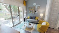 This single-floor residence in Fort Worth, TX offers a cohesive, contemporary design throughout. The living area serves as the centerpiece, styled with a cool gray and mustard yellow palette. A large sliding glass door floods the space with natural light and opens to a private outdoor patio with views of surrounding greenery. A cluster of round mirrors and bold artwork accent the feature wall above a tufted gray sofa.

The kitchen is well-equipped with dark cabinetry, white countertops, a light glass tile backsplash, and a full suite of stainless steel appliances including a range, microwave, dishwasher, and refrigerator. A deep stainless farmhouse-style sink adds a functional, upscale touch, and wood-look flooring extends throughout.

The bedroom is a calm retreat, with large windows offering outdoor views, sheer curtains that diffuse natural light, and a geometric-patterned headboard complemented by warm wood furnishings and coordinating artwork.

The bathroom features a long, dark-cabineted vanity with white countertops and wood-look flooring, leading directly to a walk-in closet with built-in shelving, providing practical and organized storage.