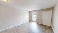 Located at 3569 Old Brandon Rd in Pearl, Mississippi, this single-story, one-bedroom, two-bathroom unit offers a practical and comfortable layout across a compact, efficiently designed floor plan. The living room greets you with light luxury vinyl plank flooring, neutral beige walls, a textured ceiling, and a window that invites natural light and outdoor views, creating a bright and welcoming atmosphere. An additional open area with the same LVP flooring provides flexible living or dining space. The bedroom is carpeted for comfort and features a natural-light window and direct access to a walk-in closet outfitted with shelving and hanging rods, offering generous storage. Two bathrooms serve the unit; one includes a wide vanity with ample counter space, under-vanity cabinetry in a muted blue-gray finish, a large mirror, and a separate water closet with a full tub-shower combination fitted with chrome fixtures. Throughout the unit, clean white trim, neutral warm-toned walls, and consistent finishes lend a cohesive, move-in-ready feel. The overall ambiance is clean, understated, and functional — well-suited for those seeking straightforward, low-maintenance living in the Pearl, MS area.