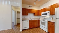 Located at 1350 W Van Buren St in Phoenix, Arizona, this single-floor unit offers a well-organized and functional layout throughout. The kitchen is a standout feature, outfitted with warm-toned wood cabinetry extending from base to upper walls, light countertops, and a full suite of white appliances including a refrigerator, electric range, built-in microwave, and dishwasher. Track lighting illuminates the workspace, and wood-look flooring runs continuously throughout the unit, lending a cohesive, clean aesthetic. The living area is generously proportioned, bathed in natural light through large windows dressed with vertical blinds, and features a ceiling fan overhead. A sliding glass door provides access to the outdoors, enhancing the sense of openness. The bedroom offers ample natural light through dual windows and includes a dedicated closet with built-in shelving for practical storage. An additional room features its own closet as well. The bathroom is finished in white tile, complete with a full soaking tub and shower combination. Throughout the unit, neutral walls and consistent wood-look flooring create a bright, airy atmosphere well-suited to the sunny Phoenix climate.