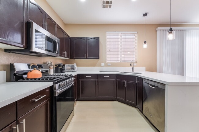 Kitchen featuring stainless steel appliances, a peninsula, dark brown cabinets, hanging light fixtur - 1179 Antoinette St