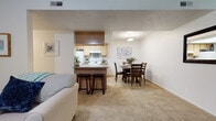 This 2-bedroom, 2-bathroom residence in West Jordan, Utah offers a well-designed single-level floor plan that balances comfort and functionality. The open-concept living and dining area forms the heart of the home, with soft carpet underfoot in the living space transitioning to stone-style tile flooring in the dining area. The living room provides a relaxed, inviting atmosphere, while the adjacent dining area offers ample room for a full dining set beneath flush ceiling lighting.

The kitchen is efficiently laid out with light wood cabinetry, a skylight that draws in natural light, white appliances including an electric range and refrigerator, and a breakfast bar with seating — ideal for casual dining. A dedicated laundry area is accessible directly from the kitchen.

The primary bedroom is generously sized with plush carpet flooring, a window for natural light, and a walk-in closet equipped with wire shelving and ample hanging space. The en-suite bathroom features tile flooring, a vanity with wood cabinetry, and a shower/tub combination. The second bedroom is equally well-proportioned, also featuring carpet flooring and a bright window. A second full bathroom serves the additional bedroom and guests, maintaining the same clean, functional aesthetic found throughout the home.