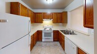 This single-floor apartment at 701 Knightsbridge Dr in Hagerstown, Maryland presents a practical and well-organized layout. The kitchen is equipped with warm oak cabinetry that extends to the ceiling, offering generous storage throughout. White appliances—including a refrigerator, electric range, and dishwasher—are complemented by light countertops and tile flooring, creating a clean, functional workspace with under-cabinet lighting above the range.

The living area features neutral carpet and opens directly to a private balcony through sliding glass doors, providing an outdoor view of the surrounding neighborhood. The carpeted bedroom areas are bright and airy, with multiple windows fitted with blinds that allow natural light to fill each room.

The bathroom is well-appointed with an oak vanity, a wide mirror illuminated by a lighted bar fixture, and a window that introduces additional natural light. An adjacent built-in closet with multi-tiered shelving adds practical storage. Tile flooring runs throughout the bathroom, maintaining a consistent and tidy aesthetic.

Overall, the unit maintains a neutral, move-in-ready palette with consistent finishes, making it a straightforward and functional residence in Hagerstown's Knightsbridge community.