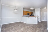 Located at 8160 Veterans Pkwy in Columbus, Georgia, this single-floor residence offers a well-designed, open-concept layout that seamlessly connects the kitchen, dining, and living areas. The living room is finished with rich hardwood-style flooring, crown molding, and a ceiling fan, while large windows and a glass-paneled exterior door invite abundant natural light throughout the space.

The kitchen is a functional centerpiece, featuring warm honey-toned cabinetry, granite countertops with speckled detailing, a classic subway tile backsplash, and stainless steel appliances including a microwave and refrigerator. A peninsula with an integrated sink and breakfast bar overhang provides additional prep space and casual seating, making it ideal for both cooking and entertaining.

The bedrooms are carpeted for comfort, with neutral tones and ceiling fans. The primary bedroom benefits from multiple windows offering outdoor views and direct access to a spacious walk-in closet with built-in shelving. An additional bedroom provides ample space with its own closet access. The bathroom is appointed with a warm wood-toned vanity, a large mirror with overhead lighting, and a full shower-tub combination. Throughout the unit, consistent crown molding and clean white trim add a polished, cohesive aesthetic.