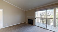 Located at 1809 Railroad Ave in Livermore, California, this single-story residence offers a thoughtfully laid-out interior with warm, neutral tones throughout. The living room serves as the heart of the home, featuring a classic tile-surround fireplace with a white mantel, crown molding, and plush carpeting underfoot. A sliding glass door opens directly onto a private balcony, flooding the space with natural light and providing pleasant neighborhood views. Adjacent to the living area, the dining space features hardwood flooring and a decorative pendant light, connecting seamlessly to the kitchen. The kitchen is well-appointed with white cabinetry, dark countertops, stainless steel appliances including a microwave and electric range, a double basin sink, and a skylight that brightens the workspace. A pass-through window connects the kitchen to the dining area. The spacious primary bedroom is carpeted and features direct access to an en suite bathroom and a walk-in closet, offering a private and functional retreat. The bathroom is finished with clean white tile surrounding a soaking tub and shower combination with chrome fixtures. An additional carpeted bedroom provides flexibility as a guest room or home office, with a window offering outdoor views. The overall ambiance is clean, comfortable, and move-in ready.