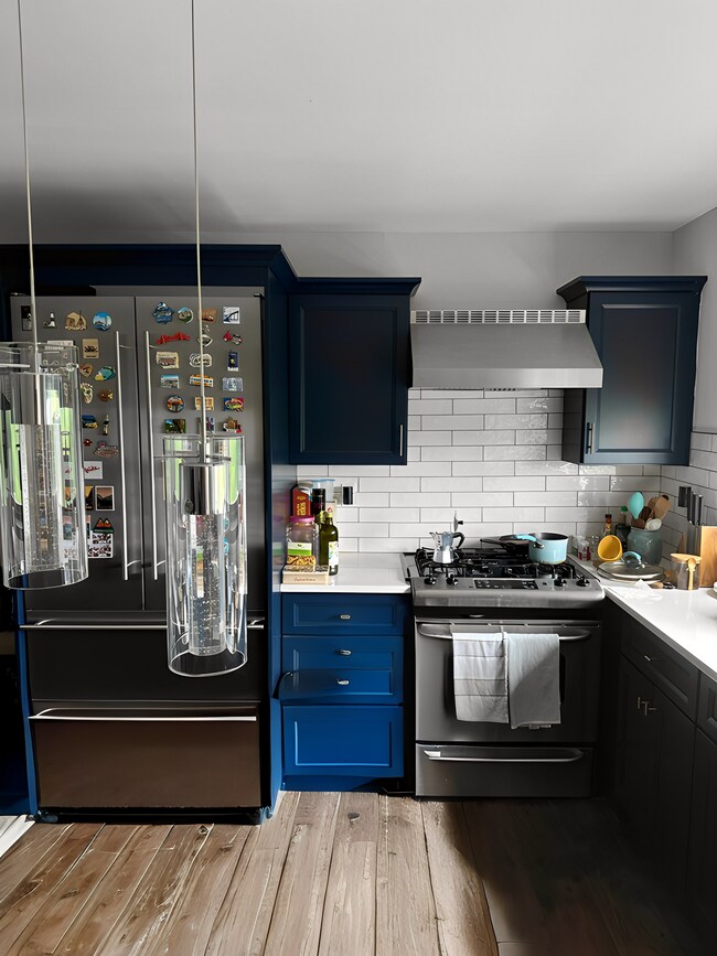 Fully renovated kitchen w/ new light fixtures, quartz countertops, blue cabinets and backsplash - 2287 Johnson Ave