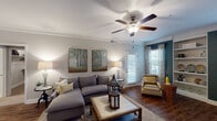 This single-story residence offers a thoughtfully designed open-concept floor plan that balances comfort and functionality. The living room serves as the heart of the home, featuring rich hardwood-style flooring, crown molding, a ceiling fan, and a teal accent wall that adds a bold design element. A private exterior door provides direct outdoor access, while large windows dressed in patterned curtains flood the space with natural light.

The kitchen is a standout, equipped with rich cherry wood cabinetry, stainless steel appliances, granite countertops, and a generous island with bar seating illuminated by pendant lighting. Track lighting and crown molding add further refinement to the space.

Two well-proportioned bedrooms each feature ceiling fans and windows with exterior views. One bedroom includes soft carpeting and nature-inspired décor, while the other showcases a striking upholstered headboard against a warm gray accent wall.

Both bathrooms are finished with dark granite countertops and undermount sinks. The full bath includes a tub-shower combination, while the second bath offers a walk-in shower and tile flooring, both reflecting a consistent and polished design aesthetic throughout the home.