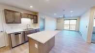 This well-appointed two-bedroom, two-bathroom residence in Clearwater, Minnesota offers a thoughtfully designed single-floor layout that maximizes functionality and comfort. The open-concept kitchen and living area forms the heart of the home, anchored by a striking center island with a marble-style countertop. The kitchen is outfitted with rich wood cabinetry, stainless steel appliances including a refrigerator, range, and microwave, plus a double sink. Recessed lighting illuminates the space, which flows seamlessly into the living area where a ceiling fan, wall-mounted climate unit, and sliding glass door leading to a private balcony with outdoor views complete the picture. Light hardwood-style flooring runs throughout the main living areas, adding warmth and continuity. Both bedrooms are carpeted and feature windows with views of the surrounding landscape, baseboard heating, and wall-mounted climate controls. The primary bedroom is generously sized and includes a walk-in closet with wire shelving. The bathrooms are clean and functional, with one featuring a full tub/shower combination with grab bars and light wood-style flooring. A dedicated laundry room with wire shelving and appliance hookups adds everyday convenience, rounding out this practical and comfortable Clearwater home.