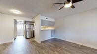 This single-floor residence offers a thoughtfully designed layout that balances open living areas with comfortable private spaces. The living area features durable hardwood-style flooring and a ceiling fan with integrated lighting, creating a bright and airy atmosphere. Natural light filters in through slatted window blinds, adding warmth to the neutral-toned walls.

The kitchen is a standout feature, boasting a U-shaped configuration with crisp white quartz countertops, gray shaker-style cabinetry, and a full suite of stainless steel appliances including a refrigerator, electric range, dishwasher, and microwave. A pass-through window and breakfast bar connect the kitchen seamlessly to the living area, enhancing the open-concept feel. The textured ceiling and coordinating hardwood-style floors carry through this zone cohesively.

The bedrooms are generously proportioned, each finished with plush neutral carpet, ceiling fans with lighting, and windows that invite natural light. The clean, bright walls provide a versatile canvas for any décor style.

The bathroom is finished with wood-look tile flooring, a white vanity with quartz countertop, and a full tub-shower combination with brushed nickel fixtures and hardware, offering a clean and modern aesthetic throughout.