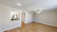 Located at 10004 Regal Park Ln in Dallas, TX, this well-appointed single-story home offers one bedroom and three bathrooms within a thoughtfully designed layout. The open-concept living and dining area is bright and welcoming, featuring warm hardwood-style flooring, crisp white crown molding, a ceiling fan with light fixture, and recessed lighting. A pass-through window connects the living space to the kitchen, creating an airy, connected feel throughout. The kitchen is outfitted with white shaker-style cabinetry, granite countertops, subway tile backsplash, stainless steel appliances including a refrigerator and electric range, and a stainless steel sink — combining modern style with functional design. The generously sized primary bedroom benefits from natural light streaming through large windows with views of the outdoors, complemented by its own ceiling fan. The bedroom is serviced by multiple bathrooms, including one featuring a tiled tub-shower combination. A hallway connects the various rooms, with closet storage also available. Neutral gray wall tones throughout lend a clean, cohesive aesthetic, making this Dallas home a comfortable and move-in-ready space.
