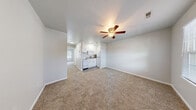 Located at 1711 N King St in Hampton, Virginia, this single-floor unit offers a straightforward and functional layout designed for comfortable everyday living. The main living area is open and airy, finished with neutral-toned carpet and crisp white walls that lend a clean, bright atmosphere throughout. A ceiling fan with a light fixture is centrally mounted overhead, providing both ventilation and ambient lighting. The kitchen is integrated into the main living space and features white cabinetry above and below, granite-patterned countertops, a stainless steel sink, and a white electric range with a ventilation hood — a practical setup efficiently tucked into the corner of the room. Adjacent to the living area, the entry foyer benefits from a window with blinds that allows natural light to filter in, along with a ceiling fan and a paneled entry door. A separate carpeted room serves as a bedroom, offering a quiet retreat with a window and an electrical panel conveniently mounted on the wall. The bathroom is clean and bright, featuring wood-look vinyl flooring, a full tub-shower combo with a white surround, and a toilet — all presented in a crisp, all-white finish. The overall ambiance of the unit is neutral and well-maintained, making it a practical and move-in ready space.