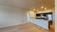 Located at 7128 NW 159th Ave in Portland, Oregon, this single-floor unit offers a well-designed, open-concept layout that seamlessly connects the living area and kitchen. Light hardwood-style flooring runs throughout the main living spaces, creating a clean and cohesive aesthetic.

The kitchen is a standout feature, equipped with a full suite of stainless steel appliances including a refrigerator, electric range, and built-in microwave. Dark espresso cabinetry provides ample storage and contrasts elegantly with the granite countertops. A peninsula with an undermount sink and additional seating space extends into the living area, making the kitchen both functional and social.

The open living area is bright and versatile, with recessed lighting and neutral wall tones that lend a calm, modern atmosphere. A dedicated laundry area is accessible from the main living space.

The unit includes two carpeted bedrooms, each featuring multiple windows fitted with blinds that allow for natural light and outdoor views of the surrounding greenery.

Both bathrooms are finished with dark cabinetry, granite countertops, and hardwood-style flooring. The primary bathroom features a dual-sink vanity with a large mirror, while the secondary bathroom includes a walk-in shower with tile surround. Together, these spaces deliver a consistent level of quality and comfort throughout the unit.