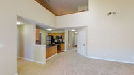 This two-floor residence offers a well-designed layout with a variety of functional spaces throughout. The main living area immediately impresses with its soaring double-height ceilings, creating an open and airy atmosphere. A staircase connects the two levels, and natural light filters through multiple windows across the home.

The kitchen is equipped with stainless steel appliances, including a refrigerator, electric range, and over-the-range microwave. Warm oak cabinetry with raised-panel detailing provides generous storage, complemented by dark granite-style countertops and hardwood flooring. The kitchen also features a dedicated laundry area with hookups nearby.

The spacious living room boasts vaulted ceilings, a classic white fireplace, and large patio doors that invite natural light and outdoor views. Soft carpet flooring runs throughout the living areas and bedrooms, adding warmth and comfort.

The bedrooms are generously sized, each featuring neutral-toned walls, carpeted floors, and windows that bring in natural light. The bathrooms include hardwood flooring, wood-tone vanities, and one full bath with a tub-shower combination. A secondary bathroom features a standalone shower and is conveniently sized.

Overall, the space presents a comfortable and functional layout suited for everyday living across two well-appointed floors.