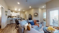 This thoughtfully designed single-floor residence offers a seamless blend of modern functionality and comfortable living. The open-concept layout connects the living, dining, and kitchen areas into a cohesive, light-filled space. The living room features warm wood-look flooring, neutral toned walls, and direct access to a private outdoor balcony through elegant French doors that invite natural light to pour in. A dedicated home office provides a quiet, focused workspace complete with warm lighting and ample room for productivity. The kitchen is outfitted with crisp white shaker cabinetry, stainless steel appliances including a gas range, microwave, dishwasher, and refrigerator, complemented by a classic subway tile backsplash and a generous peninsula with bar seating — ideal for casual dining or entertaining. The bedrooms offer restful retreats with plush carpeting, recessed lighting, and thoughtful layouts that maximize comfort and storage. The bathroom is clean and functional, featuring a full tub-shower combination, white vanity cabinetry, and wood-look flooring that ties seamlessly to the rest of the residence. Throughout the space, consistent warm-toned flooring, neutral walls, and recessed lighting create a cohesive, modern ambiance well-suited for everyday living.